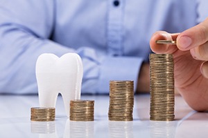 Dentist stacking coins next to a model of a tooth